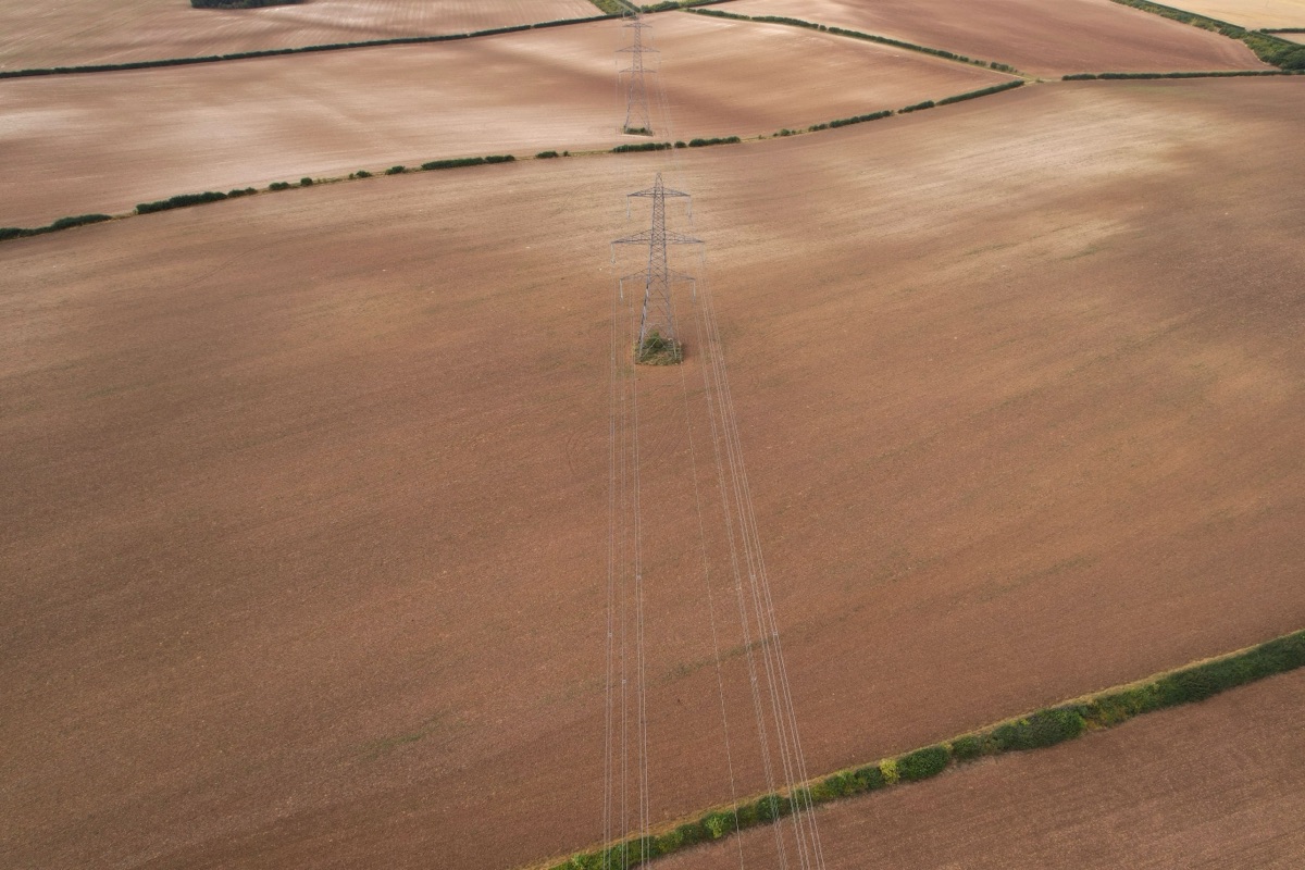Vue aérienne verticale d’un pylône électrique traversant des parcelles agricoles